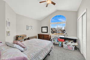 Carpeted bedroom featuring ceiling fan, a closet, and vaulted ceiling