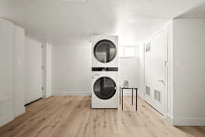 Washroom featuring stacked washing maching and dryer and light wood-type flooring