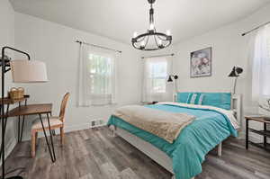 Bedroom with a chandelier and hardwood / wood-style floors