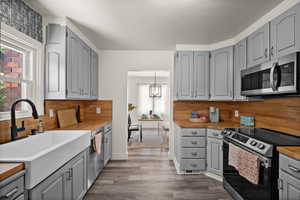 Kitchen featuring sink, appliances with stainless steel finishes, gray cabinets, and tasteful backsplash