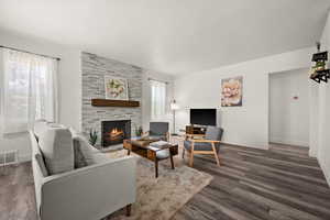 Living room with a tiled fireplace and dark hardwood / wood-style flooring