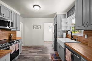 Kitchen featuring stainless steel appliances, gray cabinetry, and wooden counters