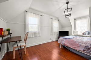 Bedroom featuring vaulted ceiling, a notable chandelier, and hardwood / wood-style flooring