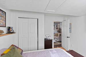 Bedroom with light wood-type flooring, a closet, and a textured ceiling