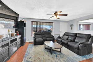 Living room featuring wood-type flooring, a textured ceiling, and ceiling fan