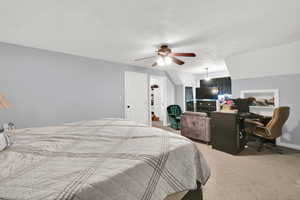 Carpeted bedroom with a walk in closet and ceiling fan