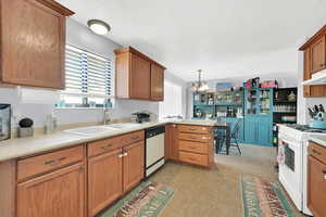 Kitchen featuring pendant lighting, sink, white appliances, and a wealth of natural light