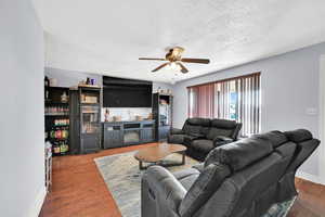 Living room with ceiling fan, hardwood / wood-style floors, and a textured ceiling