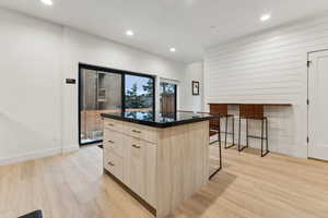 Kitchen featuring light hardwood / wood-style flooring, light brown cabinets, a breakfast bar, and a center island