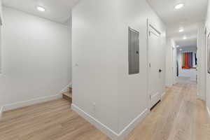 Hallway with light wood-type flooring and electric panel