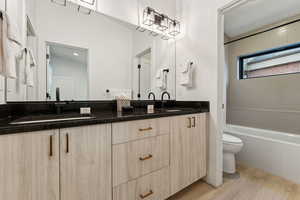 Full bathroom featuring toilet, vanity, tiled shower / bath combo, and hardwood / wood-style floors