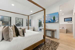 Bedroom with light hardwood / wood-style floors, access to outside, and vaulted ceiling