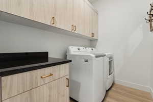 Laundry room featuring cabinets, separate washer and dryer, and light hardwood / wood-style floors