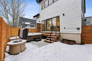 Snow covered patio featuring a hot tub and a fire pit