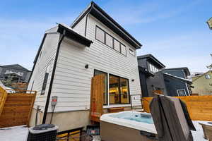 Rear view of house with central air condition unit and a hot tub