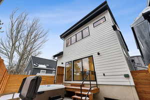 Back of house with a hot tub