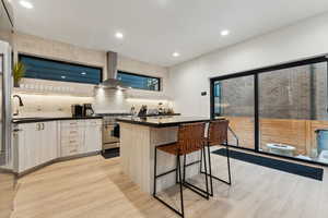 Kitchen with a center island, extractor fan, sink, high end stainless steel range oven, and light hardwood / wood-style flooring