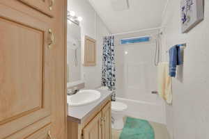 Full bathroom featuring toilet, shower / bathtub combination with curtain, and vanity