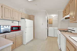 Kitchen featuring white appliances, washer and clothes dryer, a textured ceiling, light brown cabinetry, and crown molding