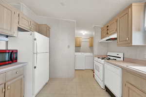 Kitchen featuring separate washer and dryer, ornamental molding, light brown cabinetry, and white appliances