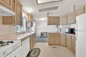 Kitchen featuring sink, light brown cabinets, and white appliances