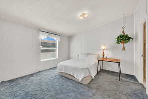 Bedroom with a textured ceiling and carpet flooring