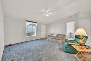 Carpeted living room featuring ceiling fan