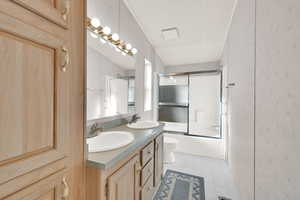 Full bathroom featuring a textured ceiling, combined bath / shower with glass door, toilet, and vanity