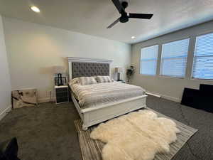 Bedroom featuring ceiling fan, dark colored carpet, and a textured ceiling