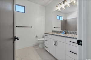 Bathroom with toilet, vanity, and a healthy amount of sunlight