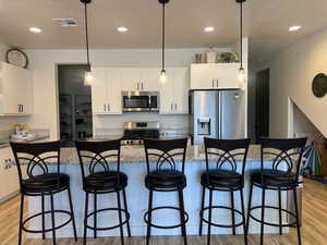 Kitchen featuring a center island, white cabinetry, stainless steel appliances, dark stone counters, and a kitchen breakfast bar