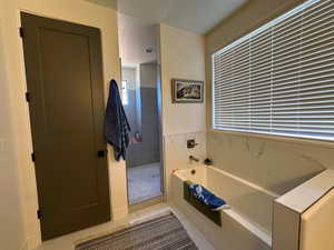 Bathroom with tile patterned flooring, a textured ceiling, and shower with separate bathtub