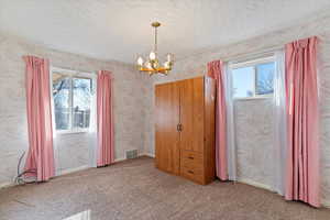 Interior space with carpet, an inviting chandelier, plenty of natural light, and a textured ceiling