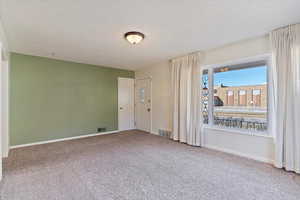 Empty room featuring carpet flooring and a textured ceiling