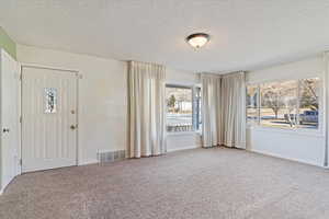 Entryway with a textured ceiling and carpet flooring