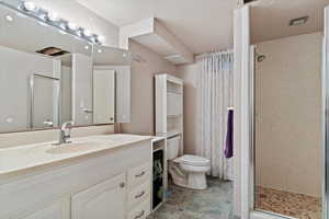 Bathroom featuring toilet, an enclosed shower, and vanity