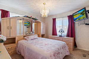 Bedroom with a textured ceiling, a chandelier, and carpet flooring