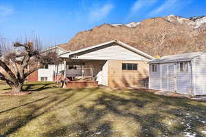 Rear view of house with a mountain view, a yard, an outdoor living space, and a shed