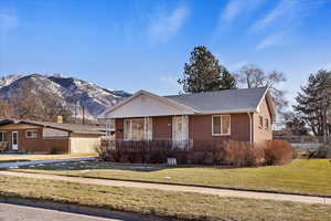 View of front of property featuring a mountain view, a front lawn, and a porch