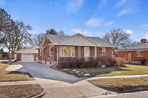 View of front of house featuring a porch, an outbuilding, a garage, and a front lawn