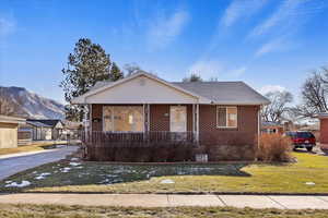 Bungalow featuring a mountain view, a front lawn, and covered porch