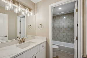 Full bathroom featuring toilet, tiled shower / bath, tile patterned floors, and vanity