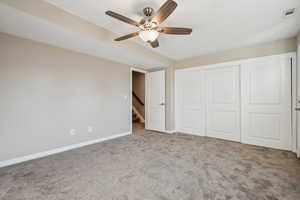 Unfurnished bedroom with ceiling fan, a closet, and light carpet