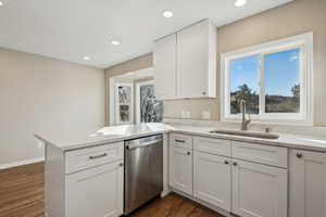 Kitchen featuring white cabinets, dark hardwood / wood-style flooring, sink, kitchen peninsula, and stainless steel dishwasher