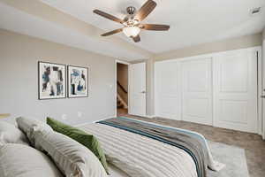 Carpeted bedroom with a closet and ceiling fan