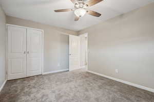 Unfurnished bedroom with a closet, ceiling fan, and light carpet