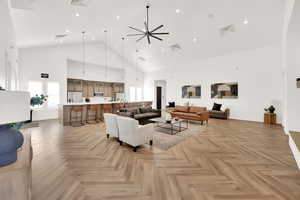 Living room featuring ceiling fan, light parquet floors, and a towering ceiling