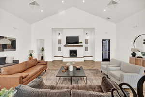 Living room with high vaulted ceiling, light parquet flooring, and a fireplace