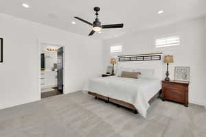 Bedroom featuring light carpet, ensuite bath, and ceiling fan