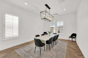 Dining room with light parquet floors and a notable chandelier